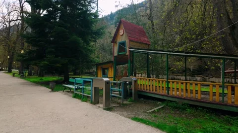 Charming wooden train station with a red roof and platform along a park path in Stock Footage 334615157