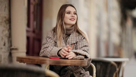 Charming young blonde girl using mobile phone while sitting at the cafe outdoors Stock Footage 152341362