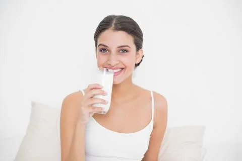 Charming young brown haired model in white pajamas drinking milk Stock Photos