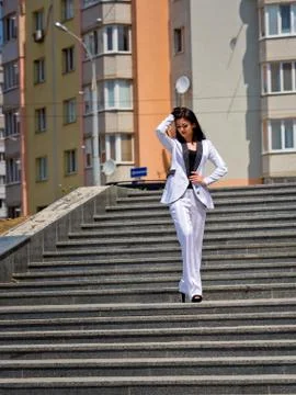 Charming young brunette posing in front of the camera on the steps in the cit Stock Photos