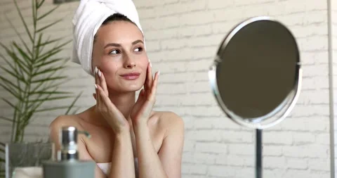 Charming young lady with bare shoulders doing massage on cheeks after morning Stock Footage 142540883