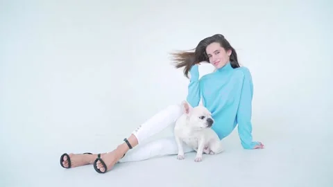 Charming young lady in blue sweater, white pants and high heels sitting on floor Stock Footage 139500437