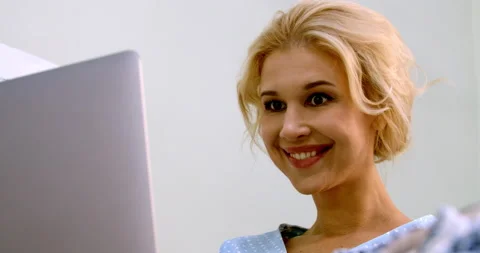 Charming young lady sitting at the table and reading something at the laptop Stock Footage 170634679