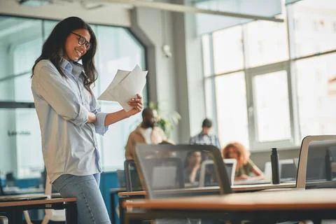 Charming young specialist checking papers at the office Stock Photos