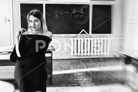 A charming young teacher holds a shackle of her glasses in her mouth Stock Photos