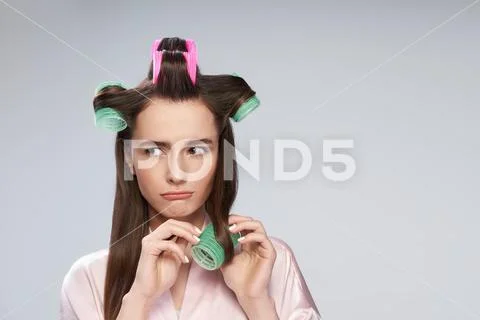 Charming young woman curling her hair with velcro rollers and pouting lips Stock Photos