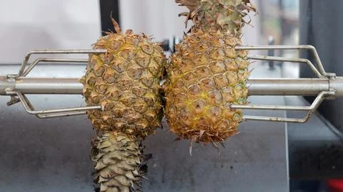 Charred pineapples roasting over open flame, Caramelized pineapples sizzling Фото
