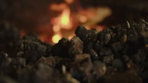 Charred rocks and coal fill the foreground as focus shifts to burning wood in Stock Footage 336425710