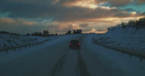 Chasing car in snowy mountain road at sunset. Stock Footage 129849598