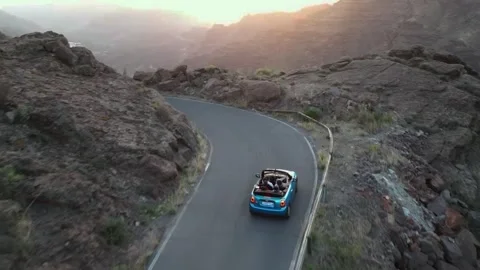 Chasing sunset and driving a mini convertible car through the mountains 库存影片 256837045
