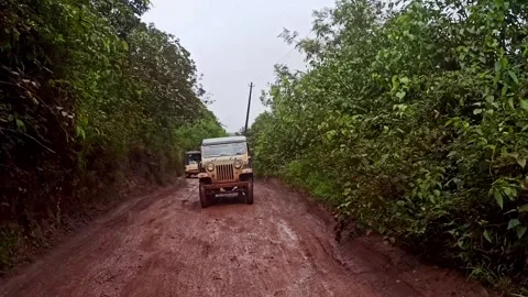 A chasing view of jeep trekking along muddy forest road through dense wilde.. Stock-Footage 346817559