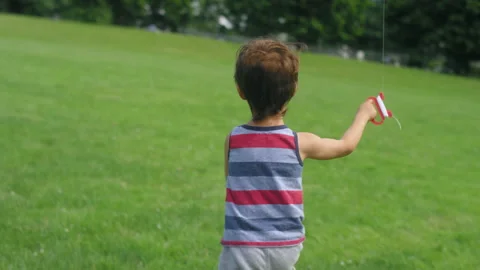 Chasing a young boy running with a kite in a big open park field Stock Footage 143622365