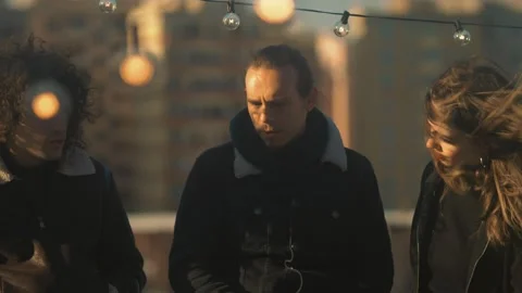 Chat between friends - three young people on the terrace at sunset talk  스톡 동영상 197743455