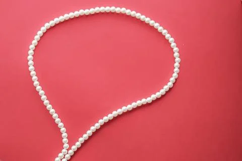 Chat message bubble made of pearl jewellery necklace on coral background Foto stock