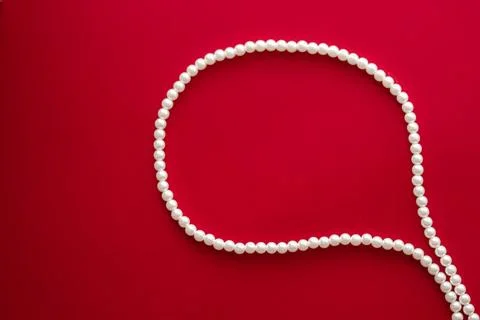 Chat message bubble made of pearl jewellery necklace on red background Foto stock