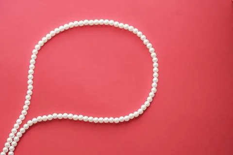 Chat message bubble made of pearl jewellery necklace on coral background Foto stock