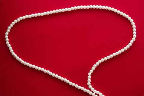 Chat message bubble made of pearl jewellery necklace on red background Foto stock