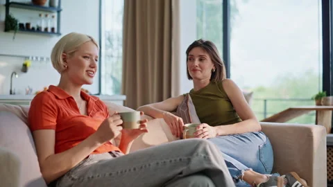 Chatting besties drinking tea at sofa interior closeup. Women sipping coffee Stock Footage 335158162