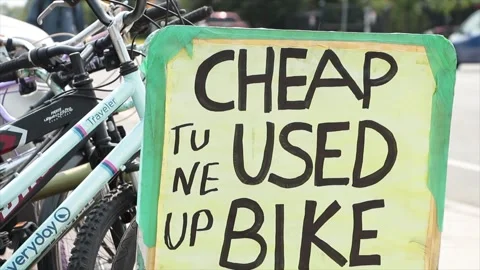 Cheap used bike tune up rectangle handwritten in black marker sign with bikes Stock Footage 249102452