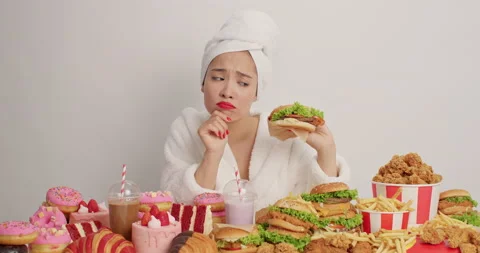 Cheat meal eating disorder concept. Dissatisfied Asian woman looks unhappily at Stock Footage 155484221