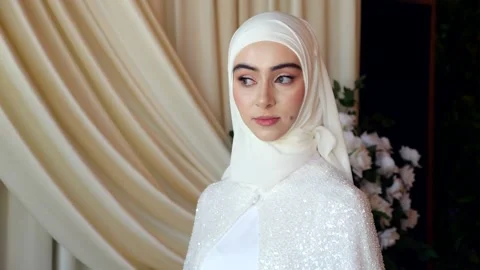 Chechen bride in hijab looks to the side standing by elegant wedding drapery Video stock 313902300