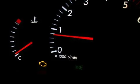 Check engine warning light glowing orange on a dark dashboard. 스톡 사진