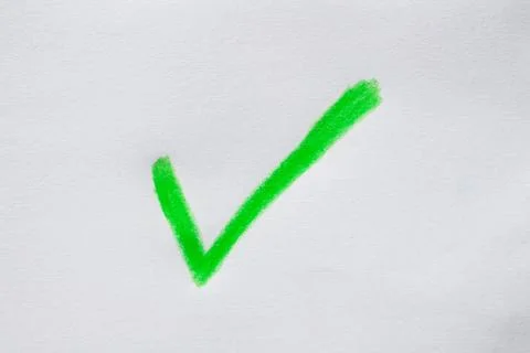 Check mark drawn on white paper with green crayons Stock Photos