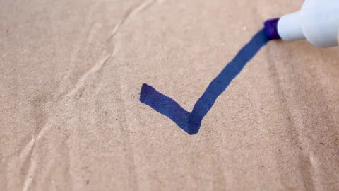 Check mark, tick, a hand drawing a check mark with a blue marker on brown Stock Footage 328232640