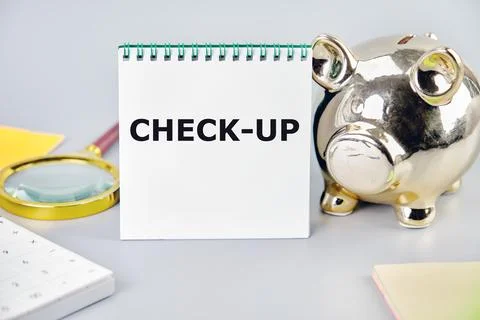 CHECK-UP A word, a text written on a notebook next to a piggy bank, a magni.. Stock Photos