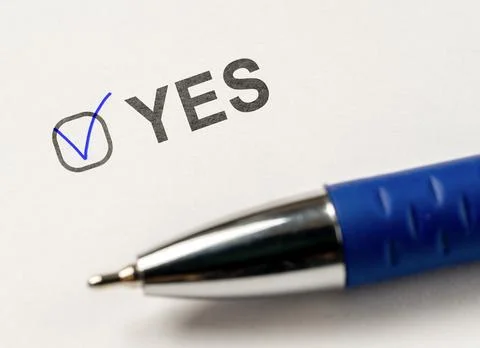 Checkbox YES. marked with tick mark and blue pen on white paper background. C Stock Photos