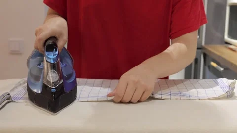 Checked cloth being pressed on kitchen ironing board Vídeos de archivo 337950553