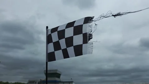 A checkered flag flaps beside a race track Stock Footage 343322434