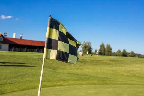 A checkered flag on a golf course signifying a hole against gold building Foto stock