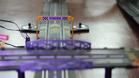 Checkered flag with word finish written on plastic gate above toy race track. Stock Footage 330538018