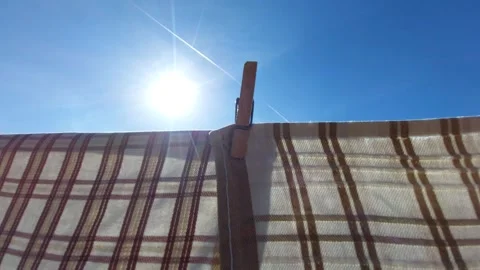 Checkered laundry drying on clothesline with bright sun flare Vídeos de archivo 334328452