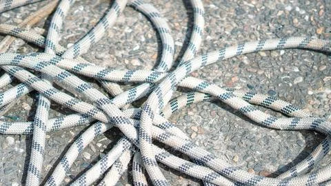 Checkered pattern mooring ropes tangled on a grey gravel ground at a pier. Stock Photos
