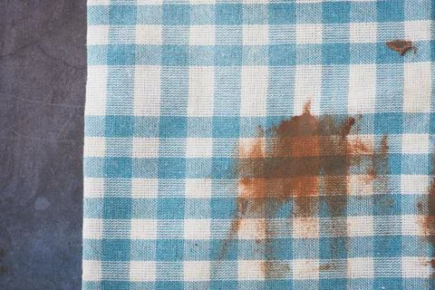 Checkered tablecloth with a stain on a dark surface Stock Photos