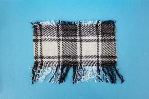 Checkered wool fabric ripped in rectangular shape on blue background Stock Photos