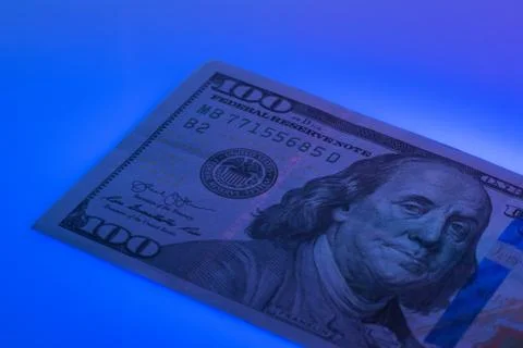 Checking 100 dollar banknote with ultraviolet lamp. Examining hundred dollar  Stock Photos