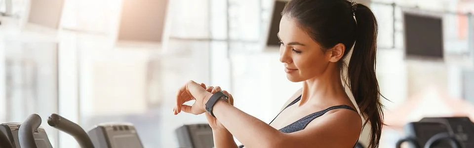 Checking all updates. Beautiful and young woman looking at her sport bracelet Stock Photos