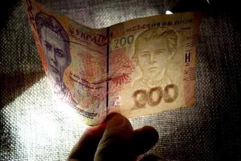 Checking the Authenticity of Ukrainian Hryvnias Under a Bright Light for Se.. Stock Photos