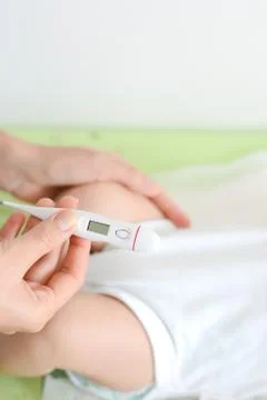 Checking baby temperature which indicates high fever on thermometer Stock-Fotos