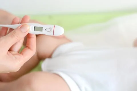 Checking baby temperature which indicates high fever on thermometer Fotos Stock