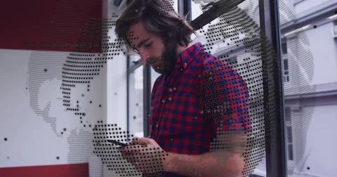 Checking bearded man wearing red-blue checkered shirt, using phone in lobby with 스톡 사진