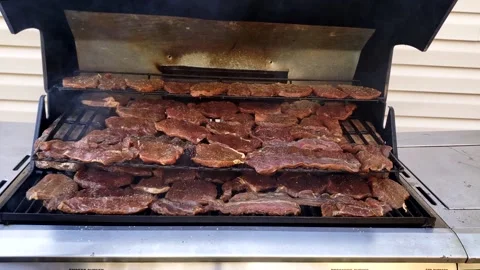 Checking beef slices being smoked in gas grill slowly dehydrating mea 스톡 동영상 163238464