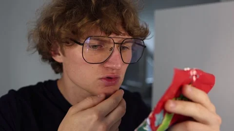 Checking candy ingredients a curious young man with big glasses studies the pack Stock Footage 312201383