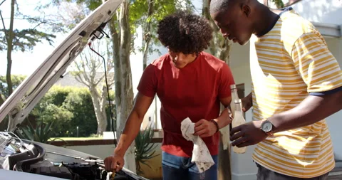 Checking car engine oil, two multiracial male friends hanging out and working Stock Footage 297593687
