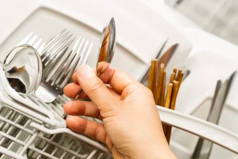 Checking for cleanliness of silverware from dishwasher Stock Photos