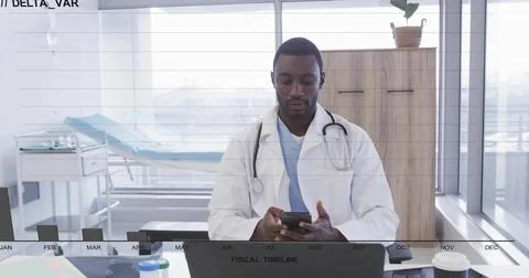 Checking doctor wearing lab coat scrolling smartphone at desk in clinic with Stock Photos