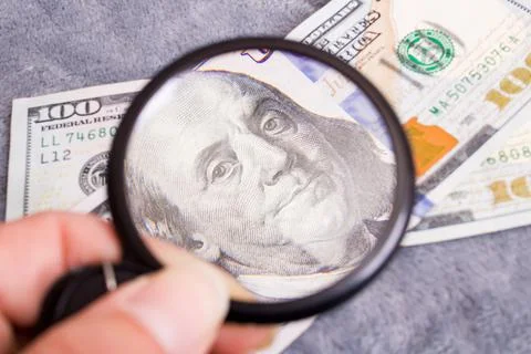 Checking dollar bill for authenticity with magnifying glass Stock Photos